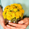 a person holding a vase of yellow flowers